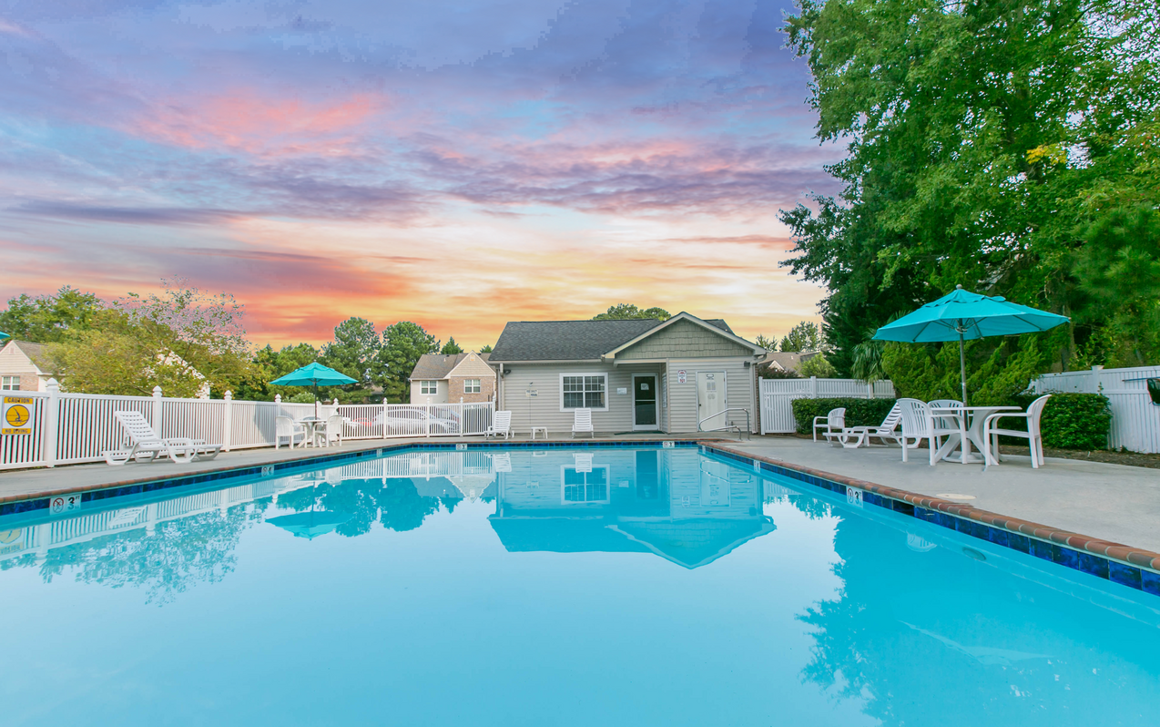 A swimming pool with a house and trees in the background.