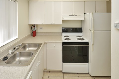 A kitchen with a stove, sink, and refrigerator.