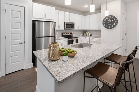 A kitchen with a granite countertop and a clock on the wall.