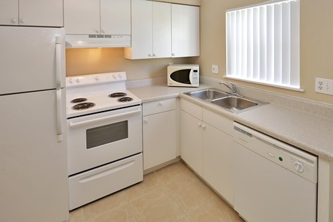 A white kitchen with a stove, oven, microwave, and dishwasher.