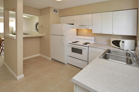 A kitchen with white appliances and a beige wall.