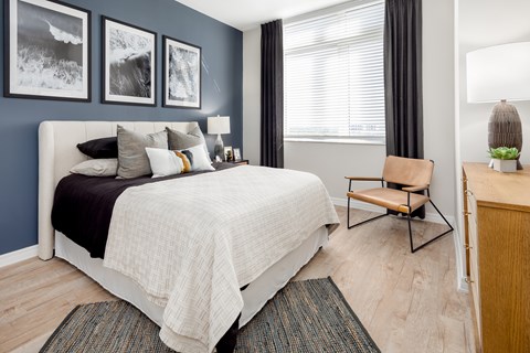 A bedroom with a bed, chair, and pictures on the wall.