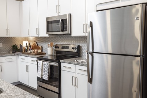 A modern kitchen with a stainless steel refrigerator and a microwave above the stove.