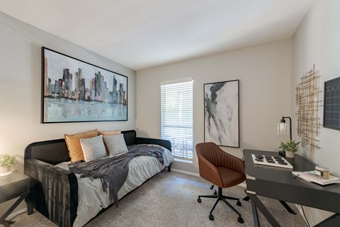 A bedroom with a bed, desk, and chair.