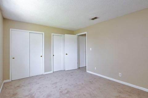 A room with four doors and carpeted floor.