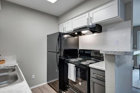 A kitchen with a black stove top oven and a black refrigerator.