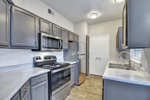 A kitchen with dark grey cabinets and stainless steel appliances.