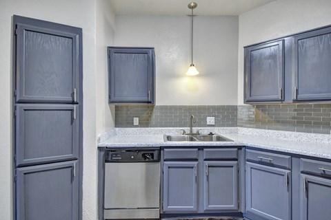 A kitchen with blue cabinets and a white counter.
