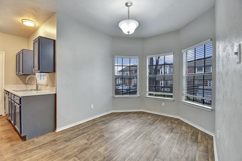 A spacious room with a kitchen area and a window with blinds.