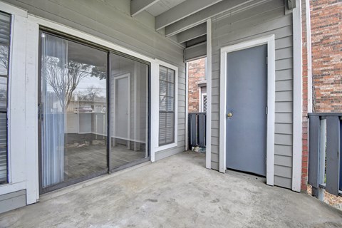 A grey door is on the right side of a patio.