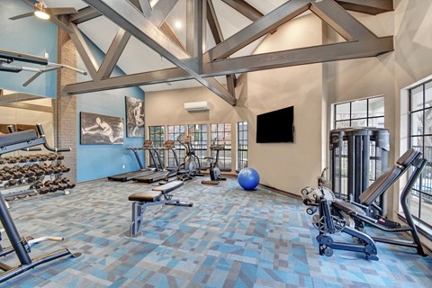 A spacious gym with a variety of exercise equipment and a television.
