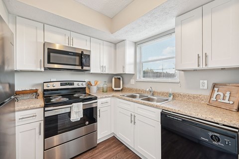 A kitchen with white cabinets and a black dishwasher.