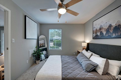 A bedroom with a large bed and a ceiling fan.