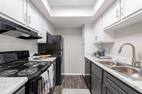 A kitchen with black appliances and white cabinets.
