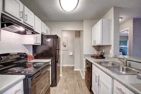 A kitchen with a black refrigerator and stove top oven.