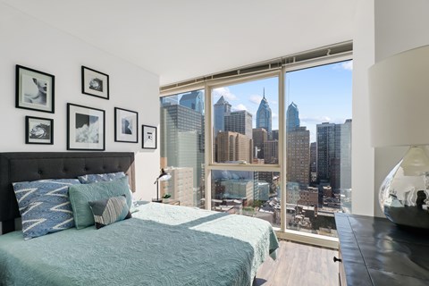 A bedroom with a large bed and a view of the city skyline.