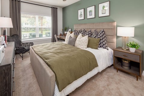A bedroom with a large bed and a chair by the window.
