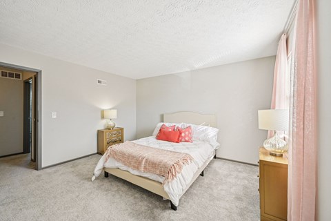 A bedroom with a bed, nightstands, and a pink curtain.