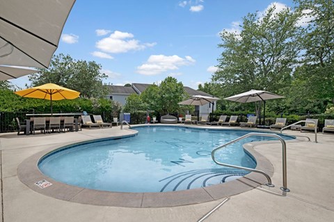 A large outdoor swimming pool with a yellow umbrella.