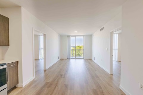A spacious, empty room with wooden floors and white walls.