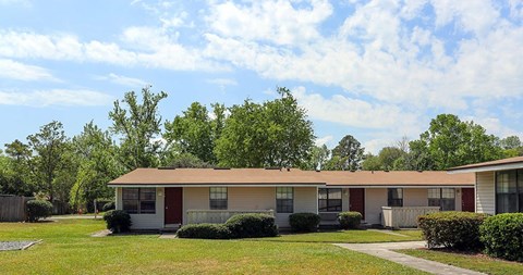 A row of houses with green lawns and trees in the background.