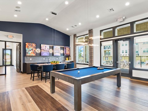 A billiards table is in the middle of a room with a bar and a pool table.