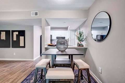 A dining area with a round mirror on the wall.
