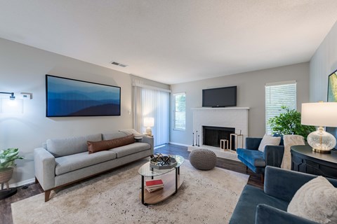 A living room with a grey couch, a coffee table, a fireplace, and a painting on the wall.