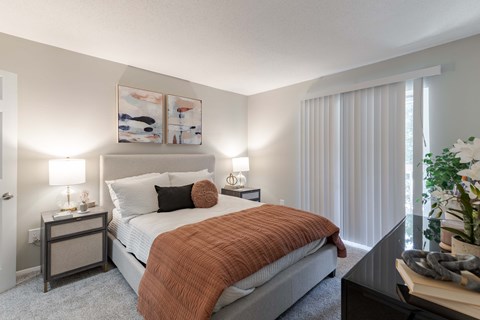 A bedroom with a bed, nightstands, and a plant.