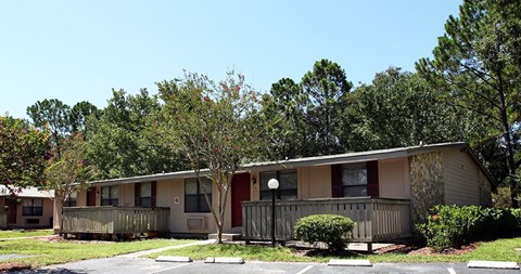A small building with a porch and a tree in front.