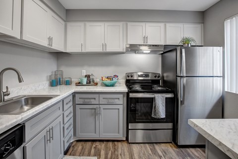 A modern kitchen with a stainless steel refrigerator, oven, and sink.