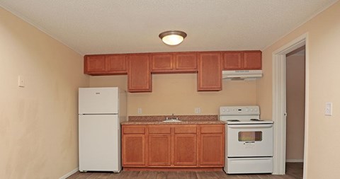 A kitchen with white appliances and wooden cabinets.