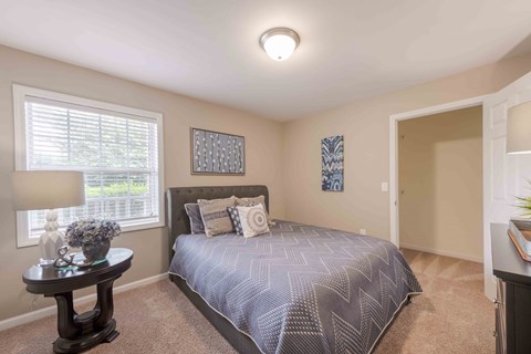 A bedroom with a bed, nightstand, and window.