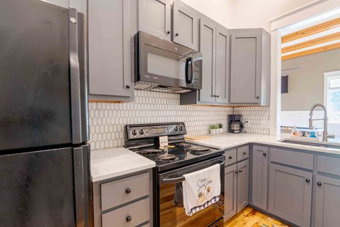 A kitchen with a black refrigerator, white countertops, and a black stove top oven.