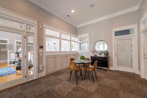 A dining room with a round mirror and a table with chairs.