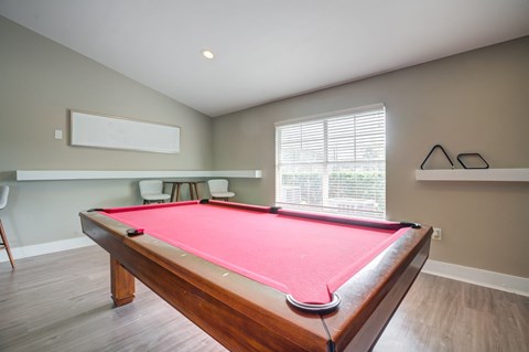 A pool table in a room with a window.