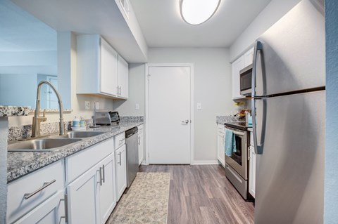 A kitchen with a refrigerator, sink, and cabinets.
