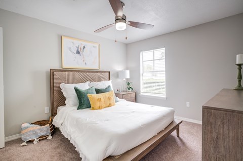 A bedroom with a white bed and a ceiling fan.