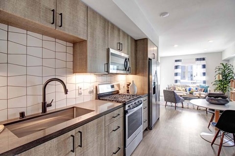 A modern kitchen with a sink, stove, and refrigerator.