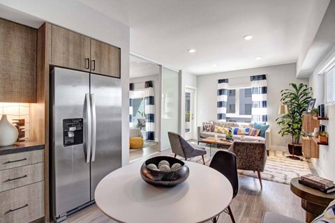 A modern kitchen with a refrigerator, a dining table, and chairs.