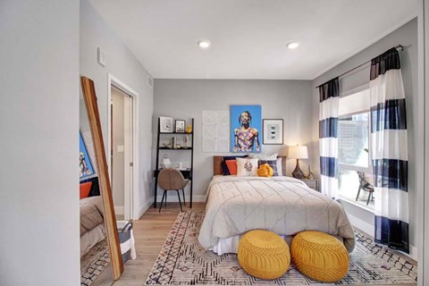 A bedroom with a bed, a chair, a desk, and a painting on the wall.