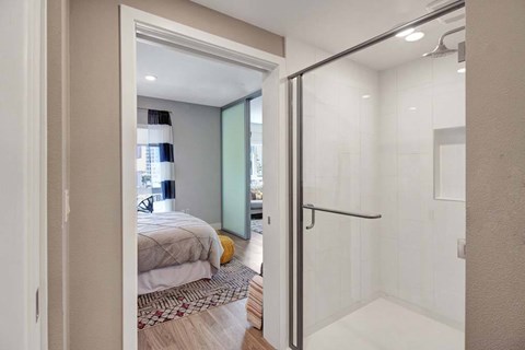 A bedroom with a bed and a glass shower door.