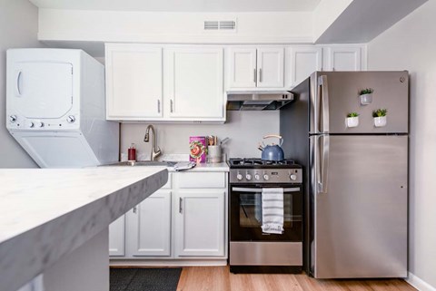 A kitchen with a stainless steel refrigerator and white cabinets.
