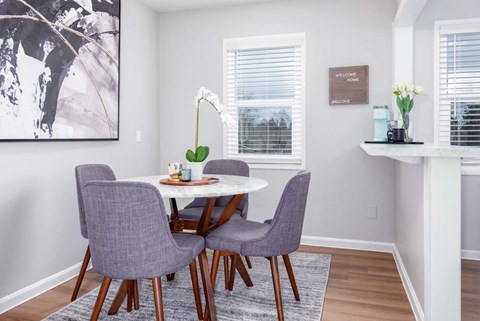 A dining room with a white table and purple chairs.