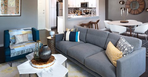 A grey couch with a yellow pillow is in the center of a living room.