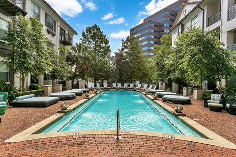 A swimming pool surrounded by lounge chairs and trees.