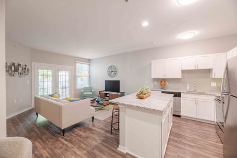 A kitchen with white cabinets and a white island with a plant on it.