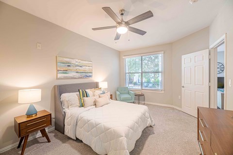 A bedroom with a large bed and a ceiling fan.