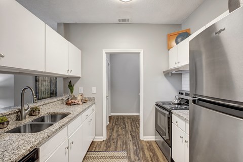 A kitchen with a sink, stove, and refrigerator.