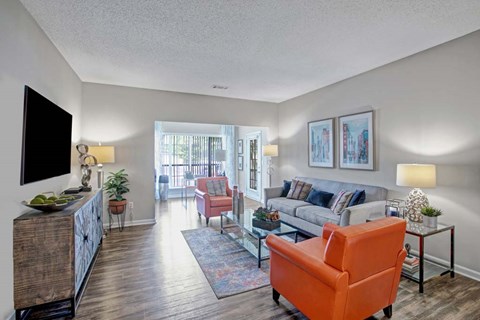 A living room with a television, couch, and chairs.